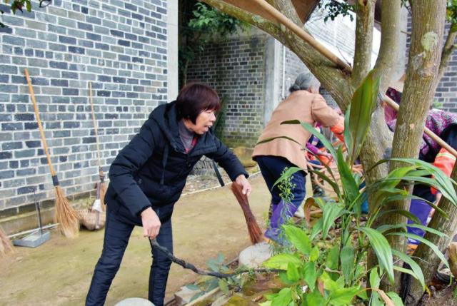 南宁女性梁彩丽带领贫困户清扫房前屋后卫生.