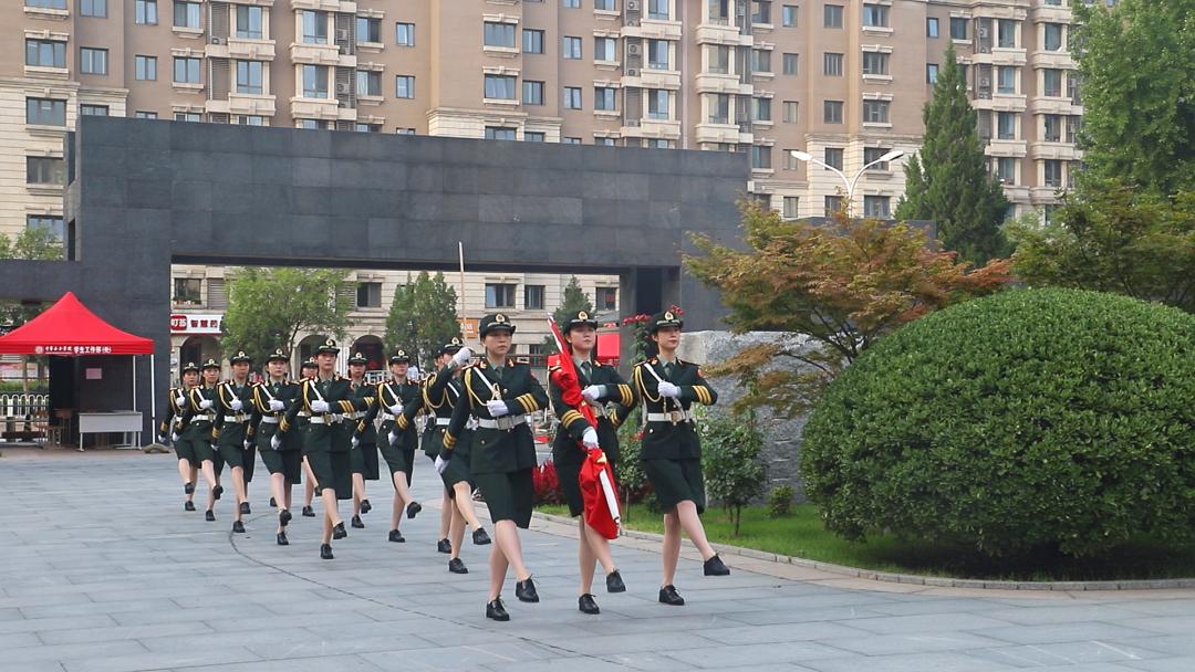 澎湃号>中华女子学院> 主楼广场前,迎着清晨的太阳,国旗班标兵护送