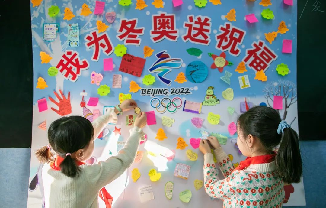 区恒昌店巷小学学生在"我为冬奥送祝福"宣传展板上粘贴自己的祝福语