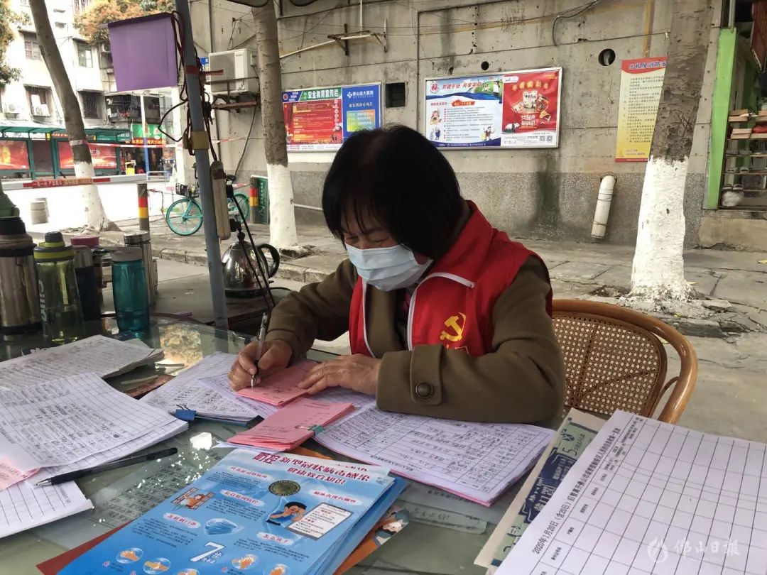桂园社区南苑党支部书记陈佩英在小区门口站岗,登记居民出入情况.