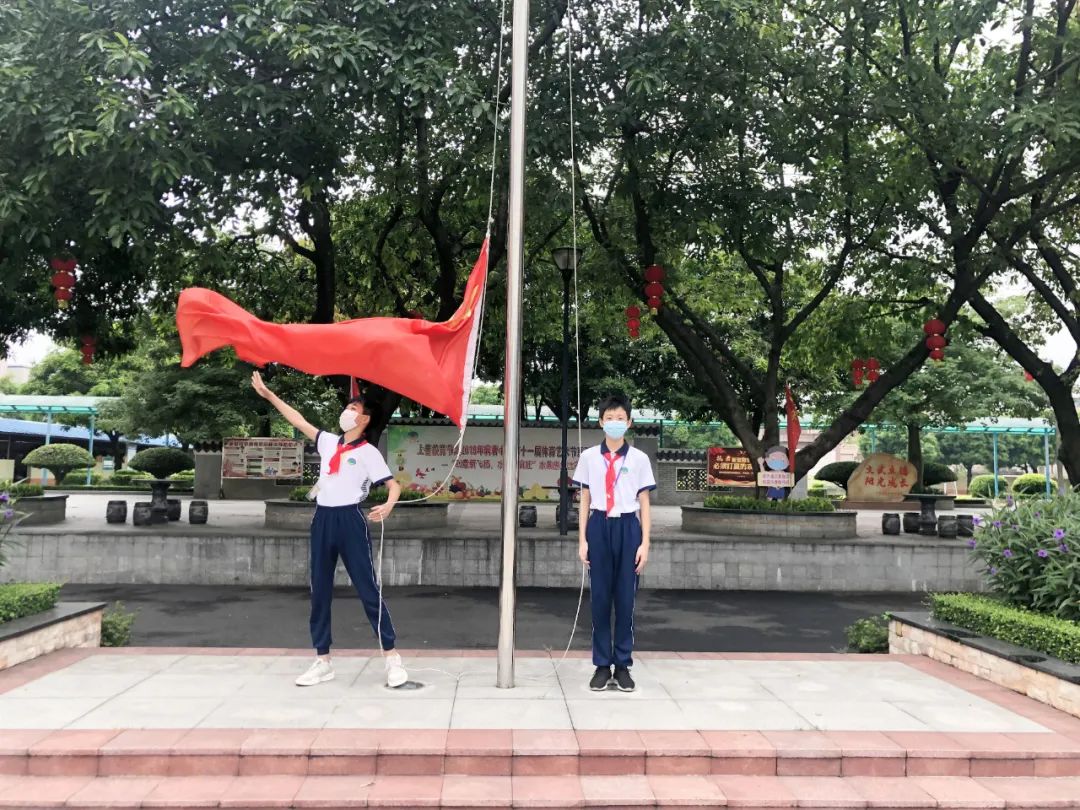 麻奢小学的小升旗手正在挥扬国旗.