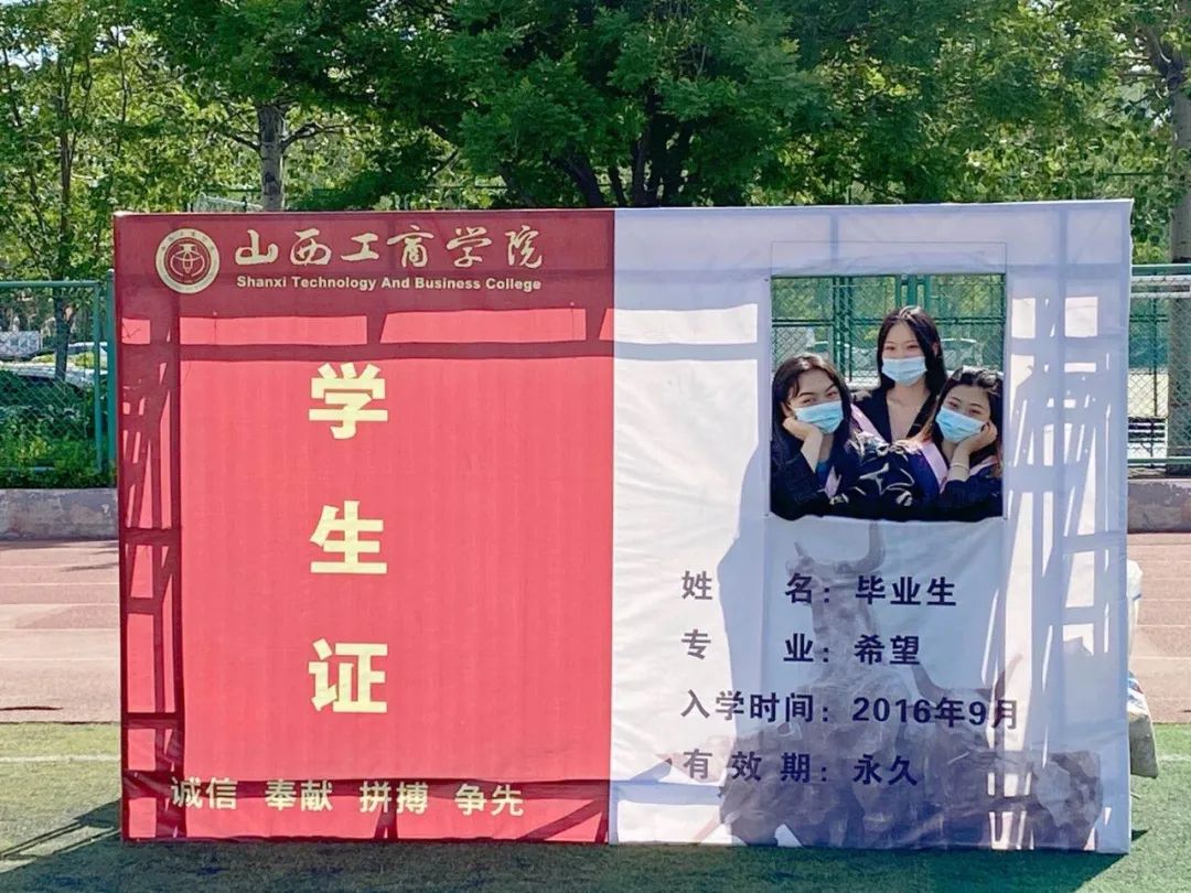 即将毕业的学生们在学校操场上的背景墙前拍照.