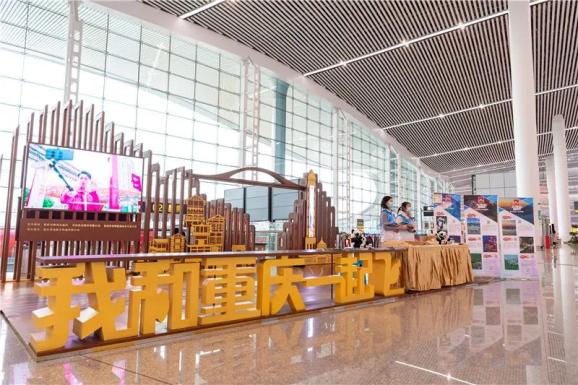 11月25日,在江北国际机场t3出发厅推介展台,过往旅客被摆放着的九龙坡