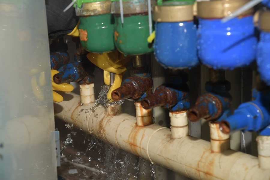 6969刘正银在空间狭窄的水表间刚拧开水管,喷洒出来的水就浇了他