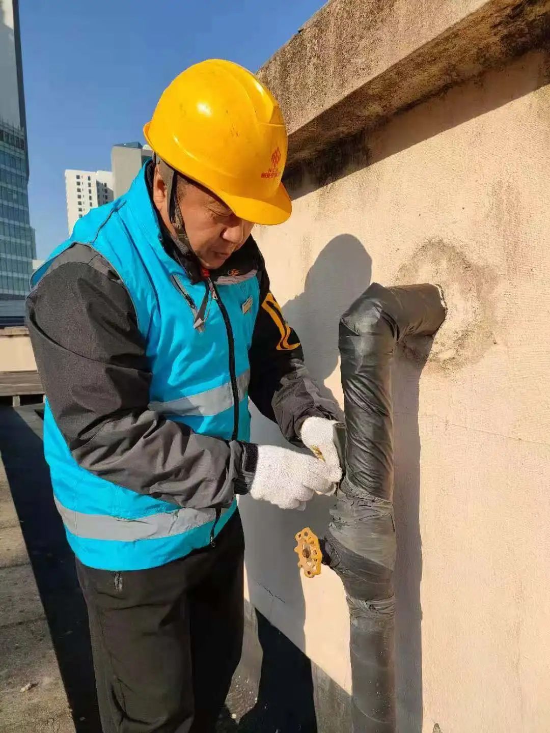 在愚园路1355弄愚园小区,维修师傅正在为裸露在外的水管加装保温材料.