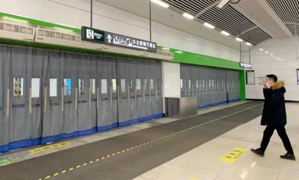 大连地铁一号线大连北站站,厚厚的门帘悬挂,一名乘客半戴口罩通过.
