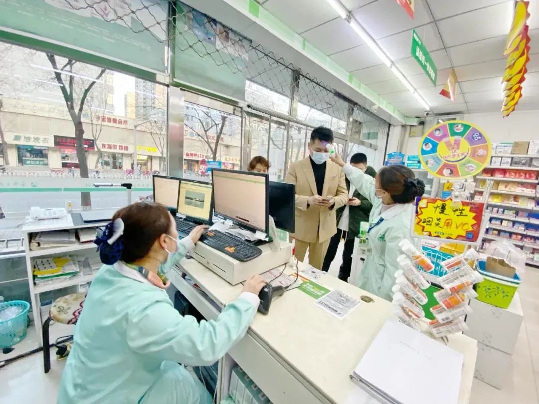 药店工作人员给进店顾客测量体温.