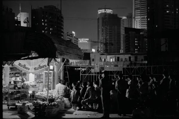 1995年,深圳罗湖佳宁娜广场,建筑工人聚在一起看电视.