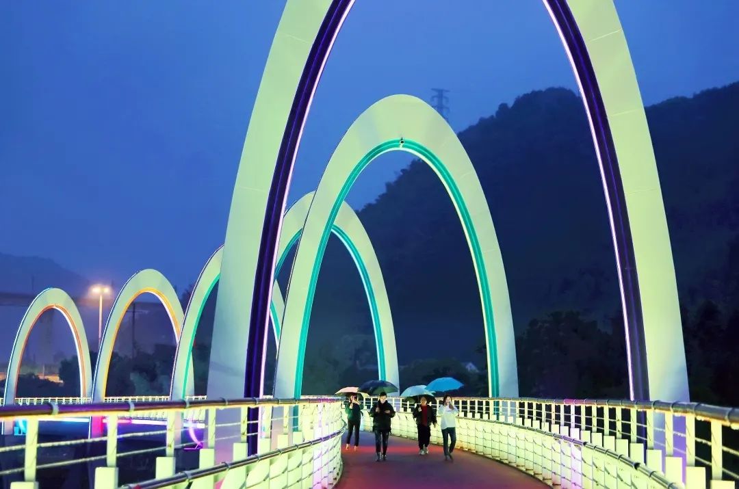 夜晚,市民們行走在彩虹橋上,燈光變幻無窮,絢麗多彩,美麗的彩虹橋也