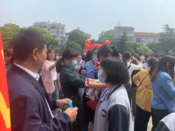 家长给孩子戴上成人纪念章胸前戴着印有新洲二中校训"厚德益智, 和谐