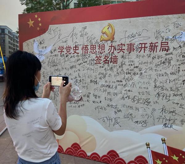 市民,朋友在学党史打卡墙上签字红色直通车车厢外,立有8块大型led灯箱