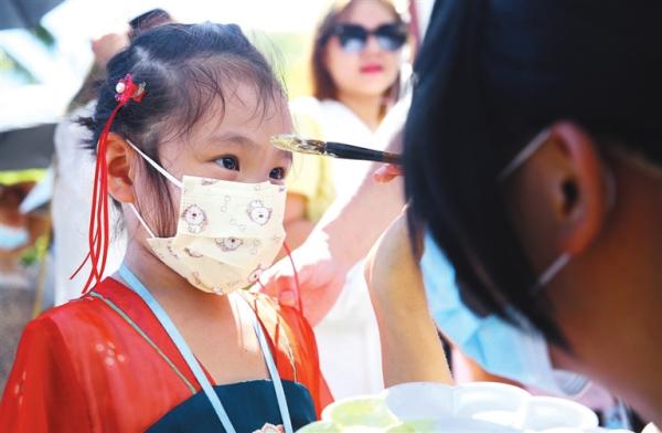 6月14日,三亚南山文化旅游区工作人员为小朋友点雄黄.