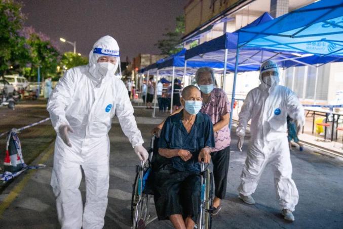 5月29日晚，志愿者蒲玉琼和陈敏协助行动不便的老人前往核酸检测点。