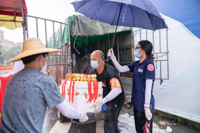 6月1日，暴雨突然袭来，志愿者姚锦祥、郭嘉欣、曹城辉冒雨搬运物资。