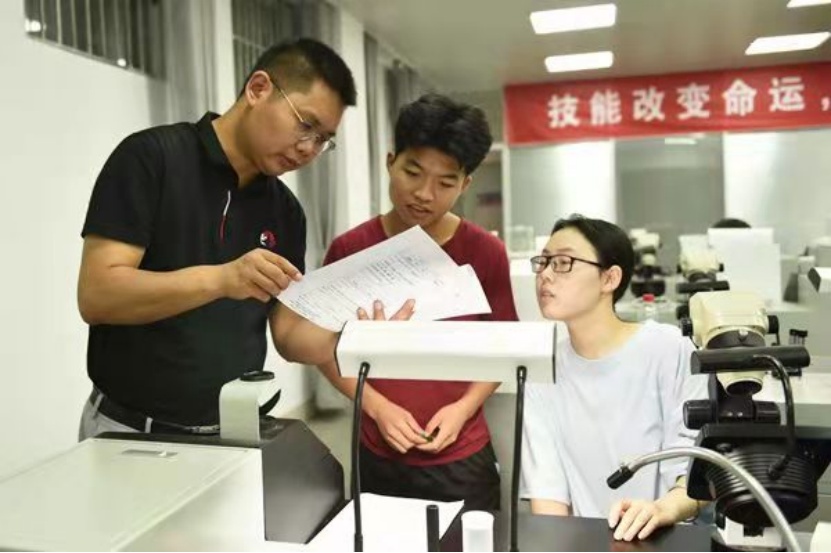 指导老师李孔亮(左一)为选手指出实验报告错误