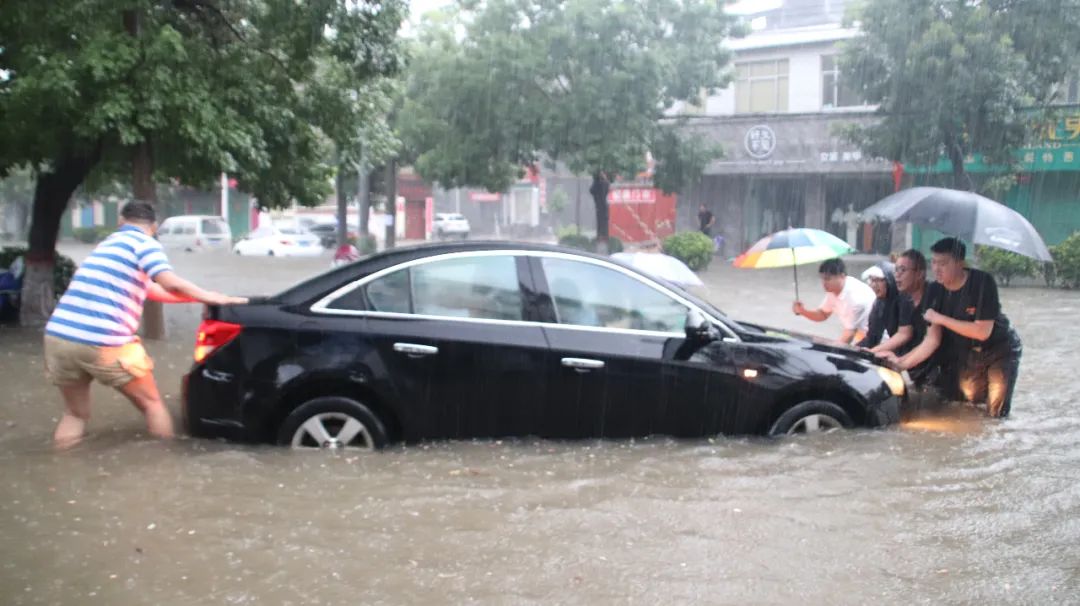 7月21日下午,汤阴县暴雨连绵,行人和车辆在城中街道艰难行驶.