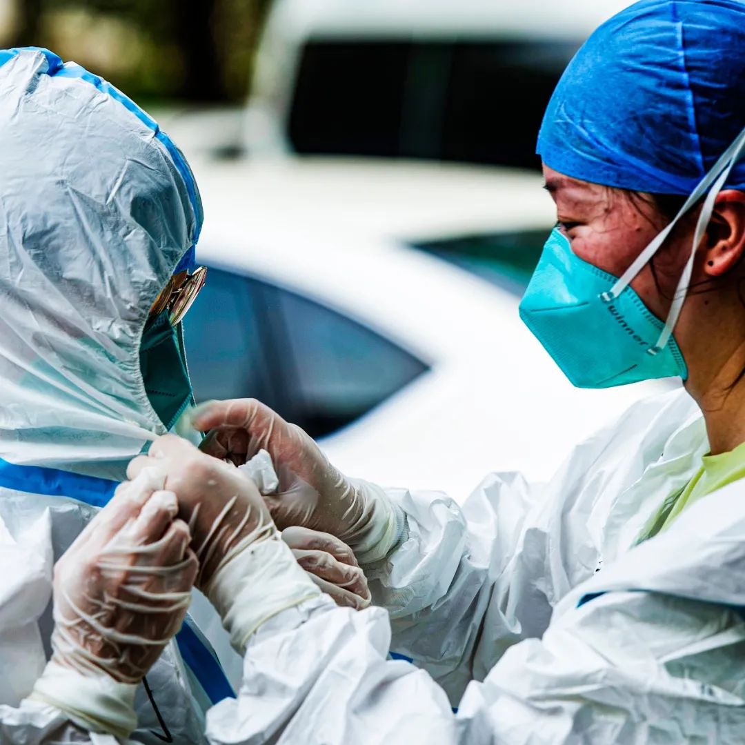 医务人员相互帮助解开早已湿透的防护服