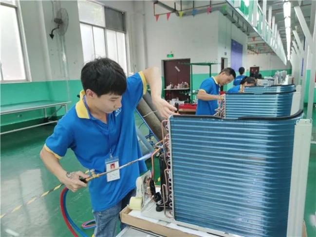 中科弘力电器(来宾)有限公司生产车间,工人正在组装空调.