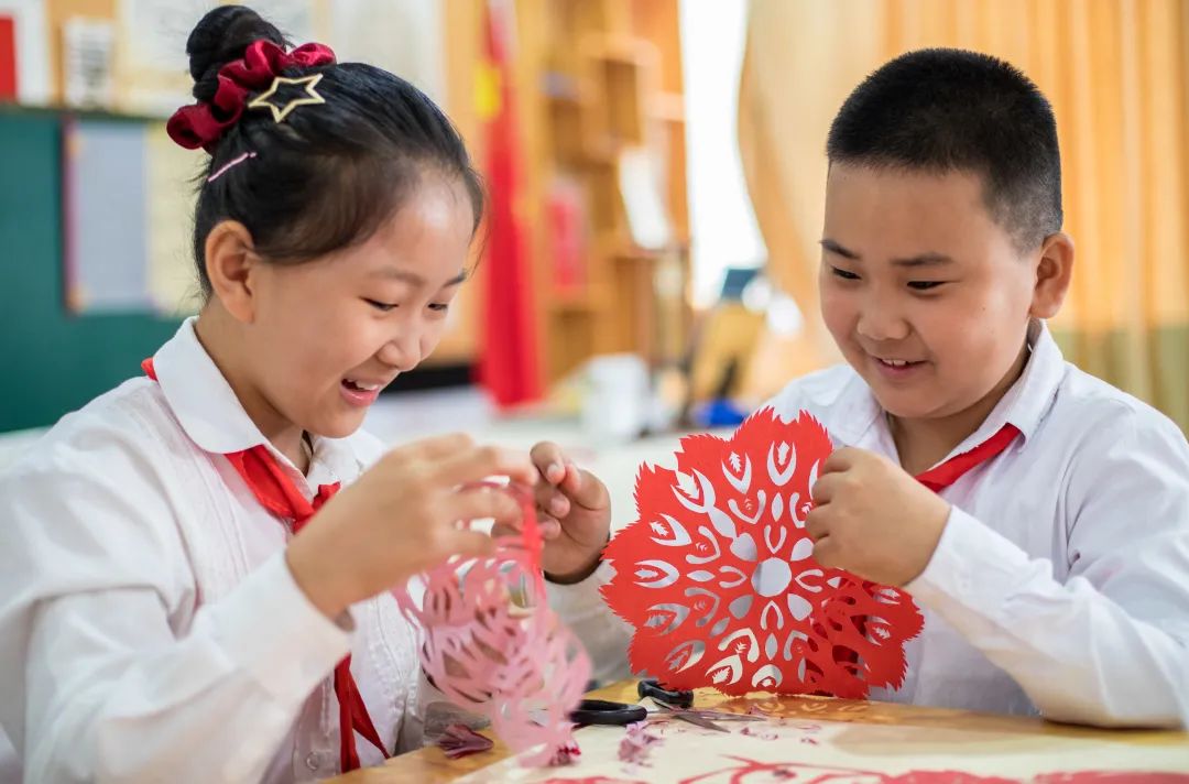玉泉区恒昌店巷小学学生在制作国庆为主题的剪纸作品和剪纸服饰