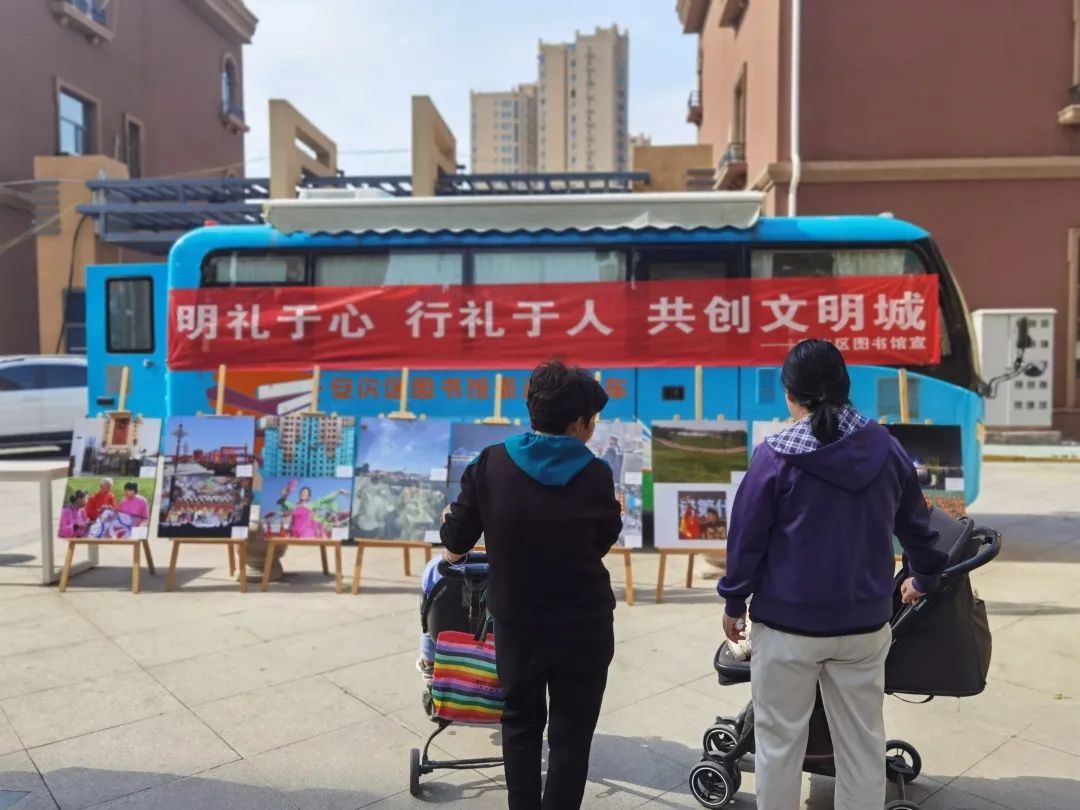 活动现场,流动图书车上悬挂着"明礼于心 行礼于人 共创文明城"的宣传