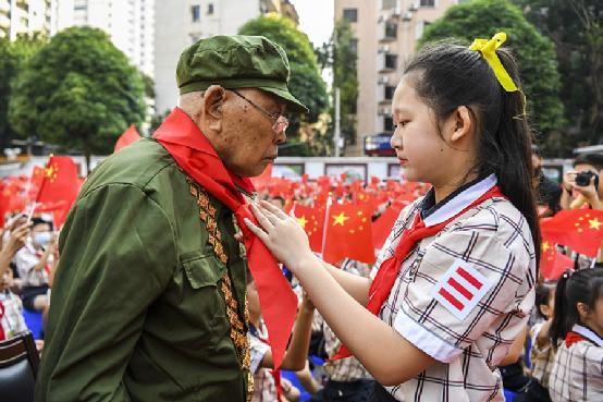 2020年8月31日，广西南宁市民主路小学的学生代表为“共和国勋章”获得者李延年戴上红领巾。图｜新华社