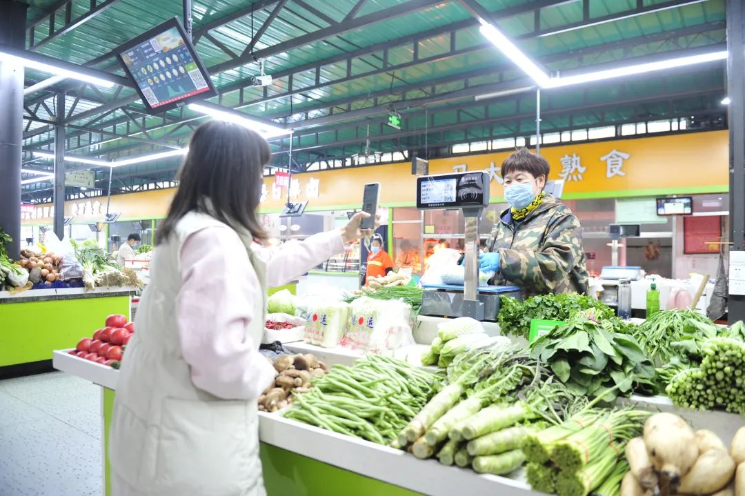在阳光大街农贸市场,顾客正在通过智能溯源电子秤进行一码支付.