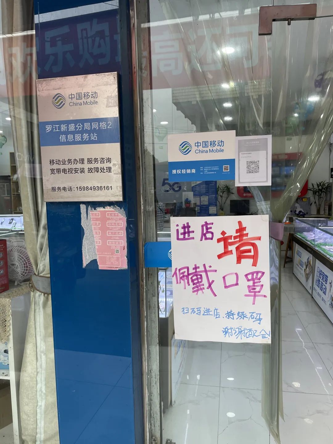 紧挨该超市的一家通信营业厅门口虽有手写的扫码进店,进店请戴口罩