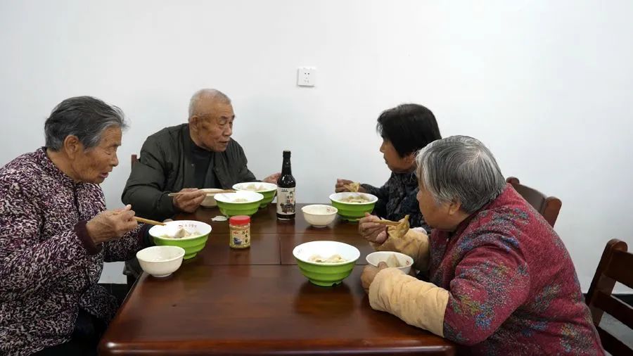 志願者與老人們圍坐在一起,吃著愛心餃子,話家常,處處洋溢著溫暖幸福