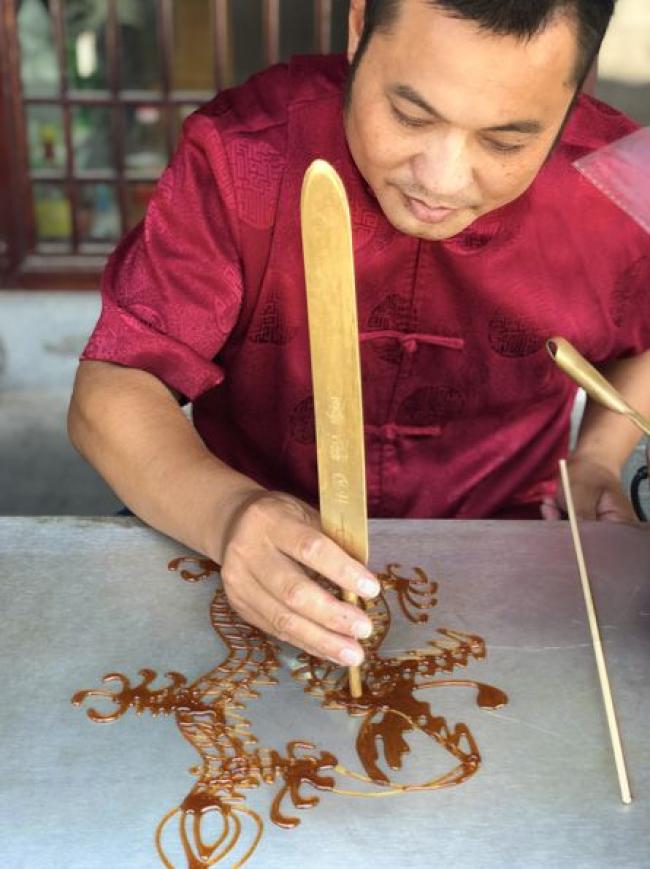 江師傅在畫龍點睛製作糖畫技巧畫糖畫的人是沒有底稿的,畫稿全在他