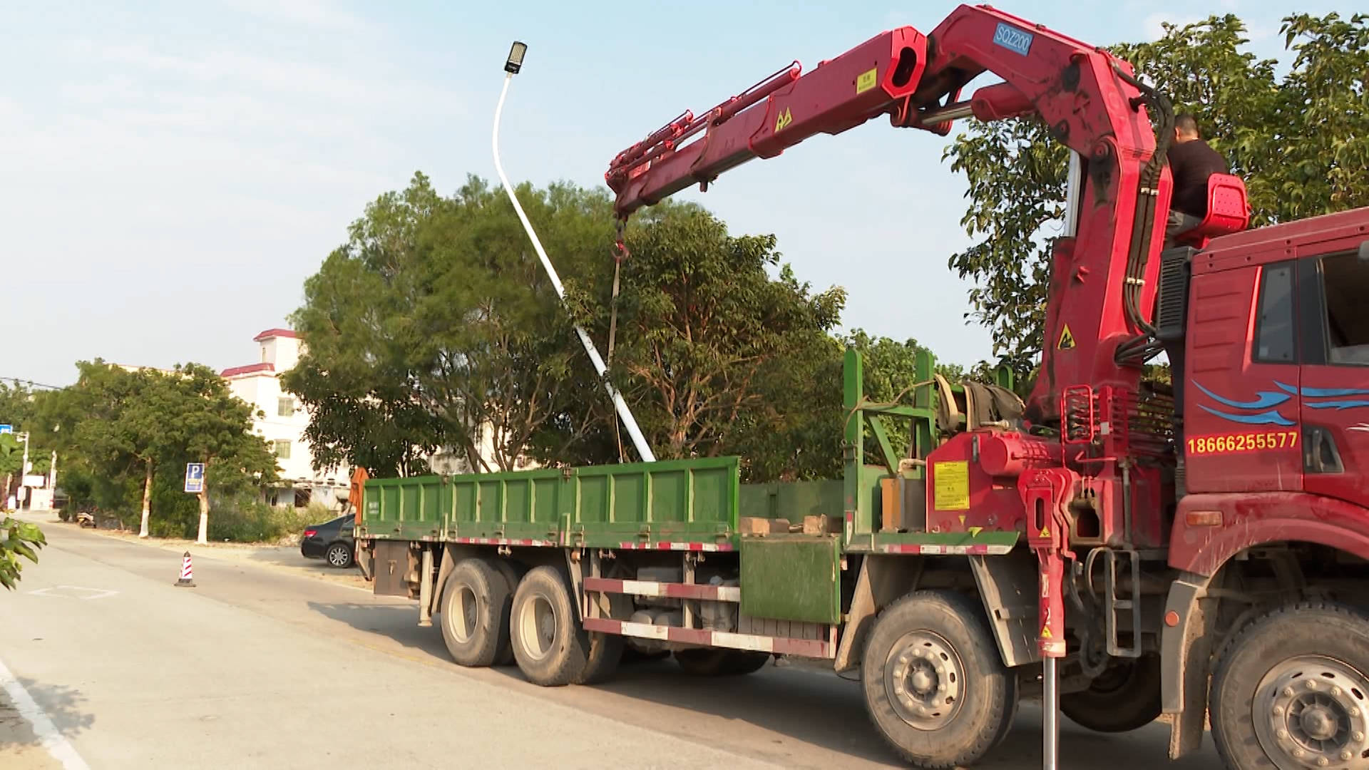 在x594线下朗段记者看到,施工人员用吊机把路灯吊装在路灯的基座上