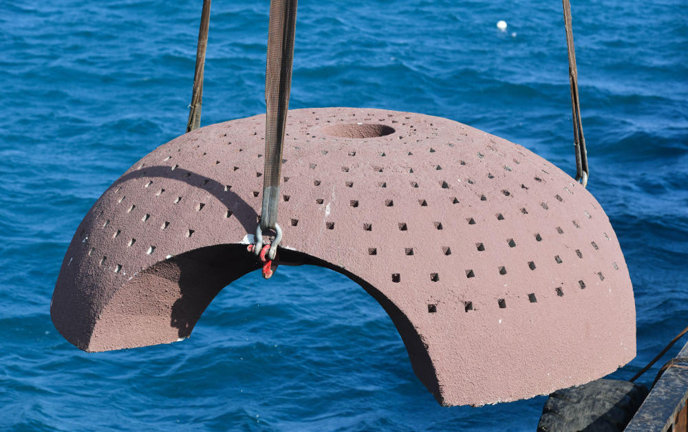 在亚龙湾相关海域,船上机械将人工生态礁吊入海中(1月19日摄).