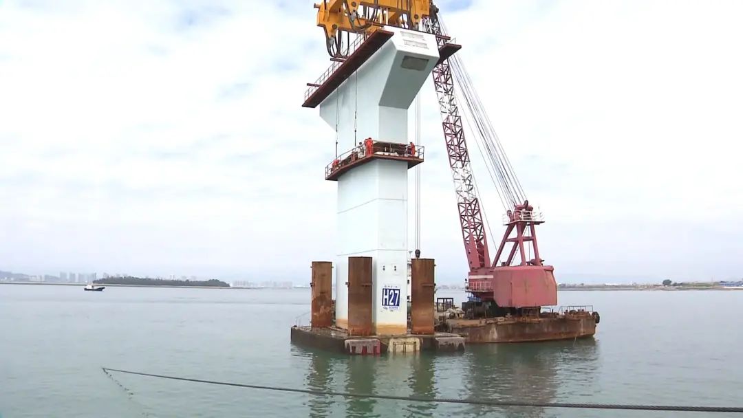 就位后,停靠在海面上的4000吨起重船,将它吊起,缓缓向27号墩靠拢.