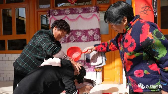 太极镇下古村杨吊果正在家中和婆婆一道给小姑子清洗头发