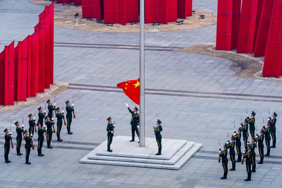 国旗护卫队迈着坚定有力的步伐护送国旗至升旗台,擎旗手迎风振臂,熟练
