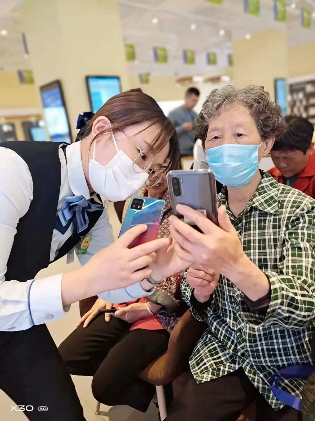 中国电信宣城分公司工作人员在帮助老年人掌握智能手机的使用方法（高琴琴/摄）