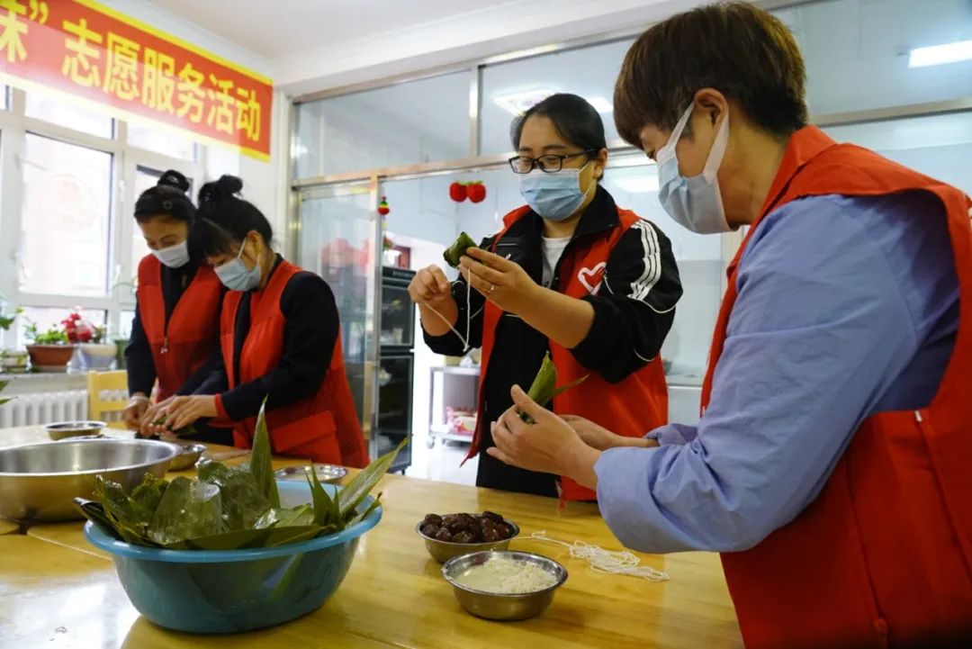 志願者在行動秀山社區新時代文明實踐站開展粽葉飄香濃情端午包粽子