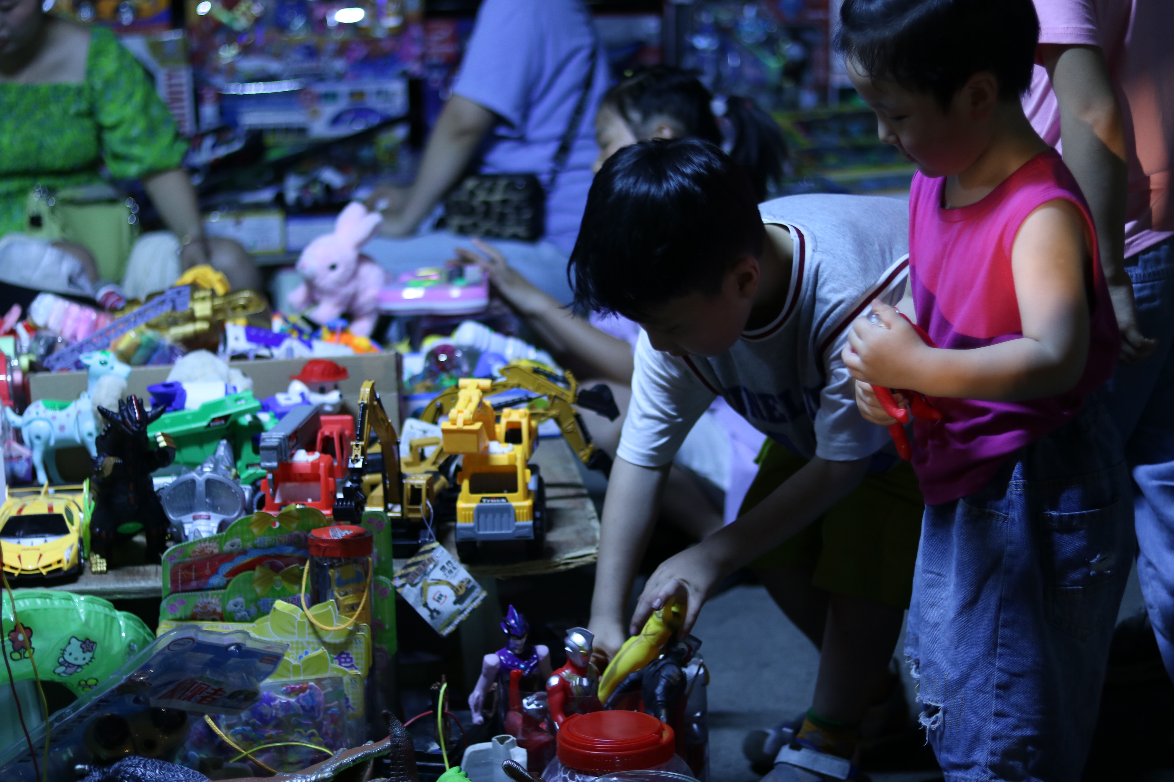 《无题》 小男孩和小女孩正在地摊玩具里选择自己喜欢的玩具