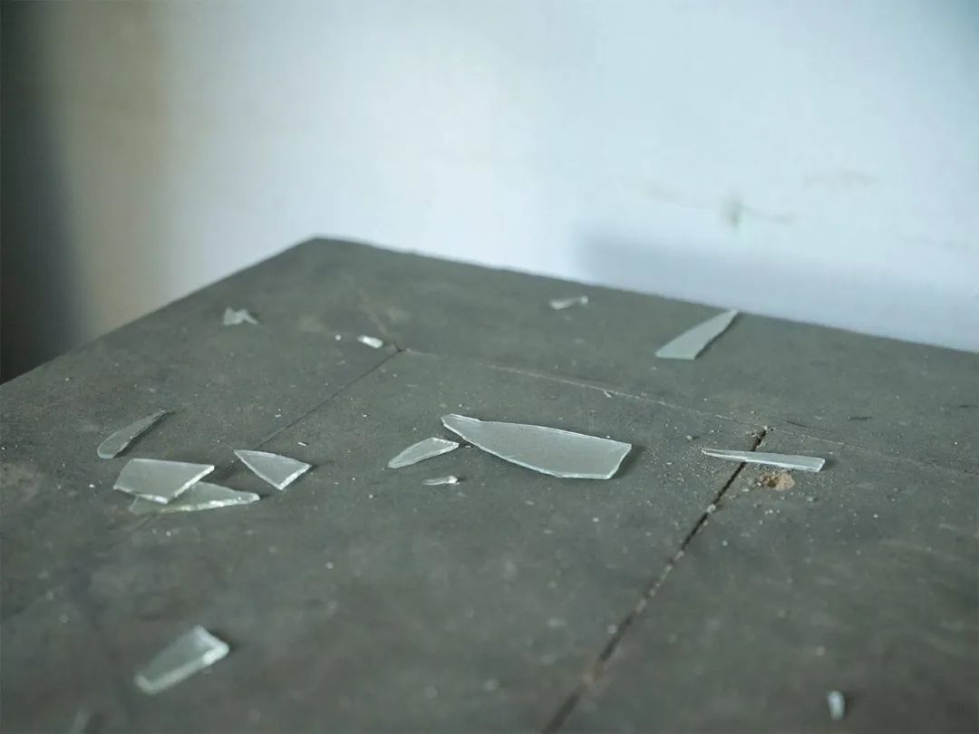 ●在汞矿住宅楼中，遗弃的(de)桌子上散落着玻璃碎片。