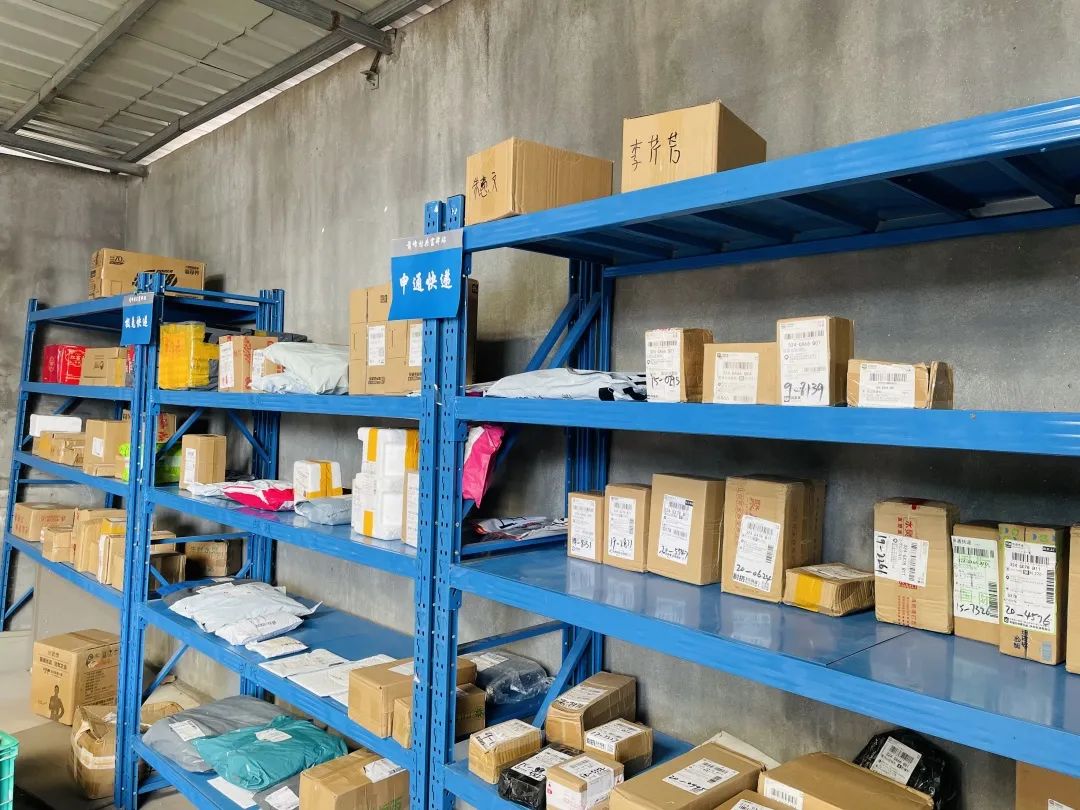 湛蓝的铁架围着刷白的毛坯墙,被整齐地摆成一圈,各类大小快递包裹以村