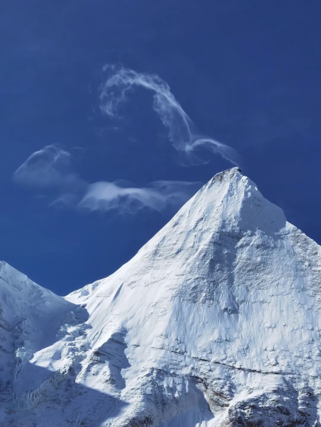 山巅云烟袅袅冷峻而圣洁终年不化的积雪覆在山顶在空寂辽阔的湛蓝下