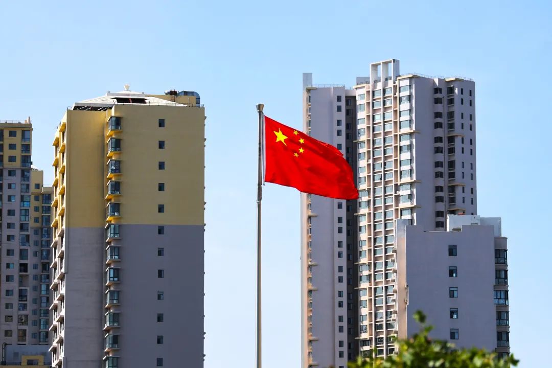 商家在店铺门前挂起崭新的国旗.工作人员调整悬挂国旗的高度.