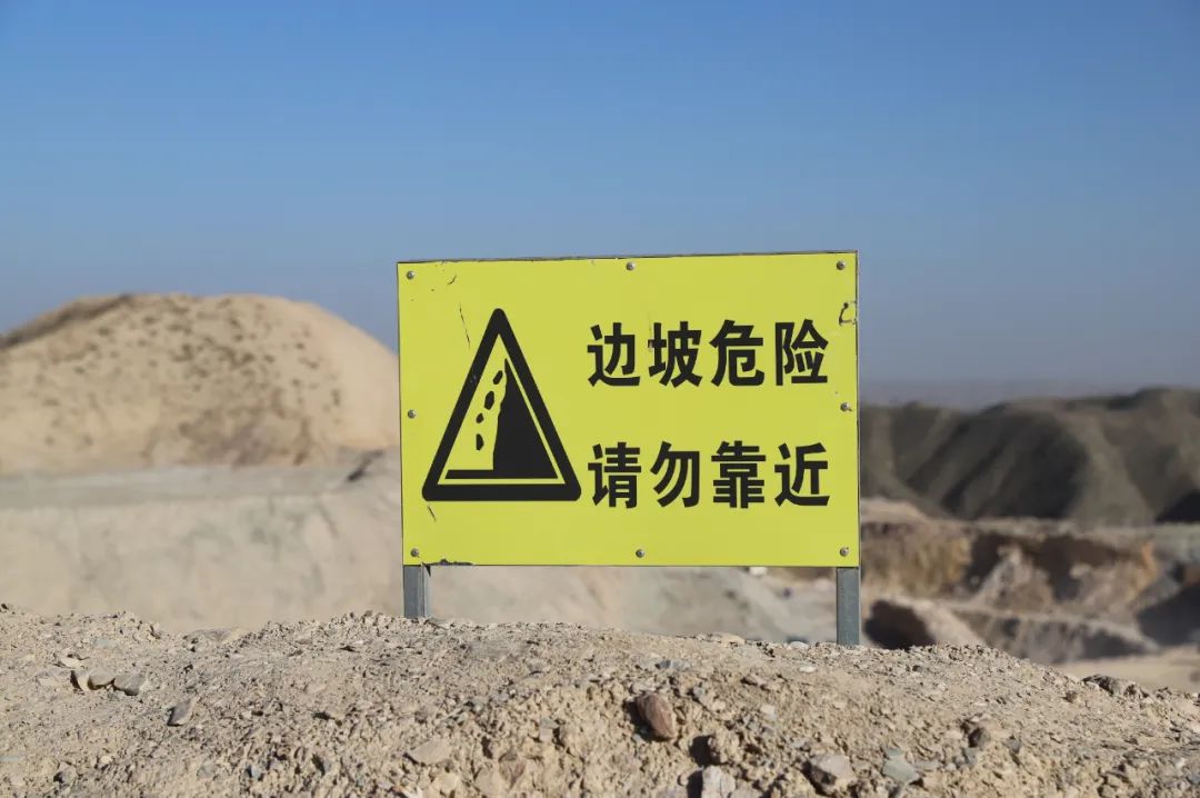 小心坠石 请勿靠近的安全警示标牌,沿露天采矿场外围边坡依次设置