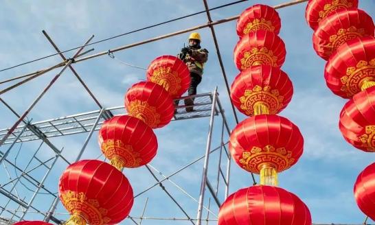 行道树上,一根根灯带缠绕树干,一个个灯笼,彩饰挂满枝头;广场上,流光