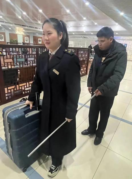 "李洪艳接过旅客的行李箱,一手拉着杨先生的盲杖,走人工通道将其带