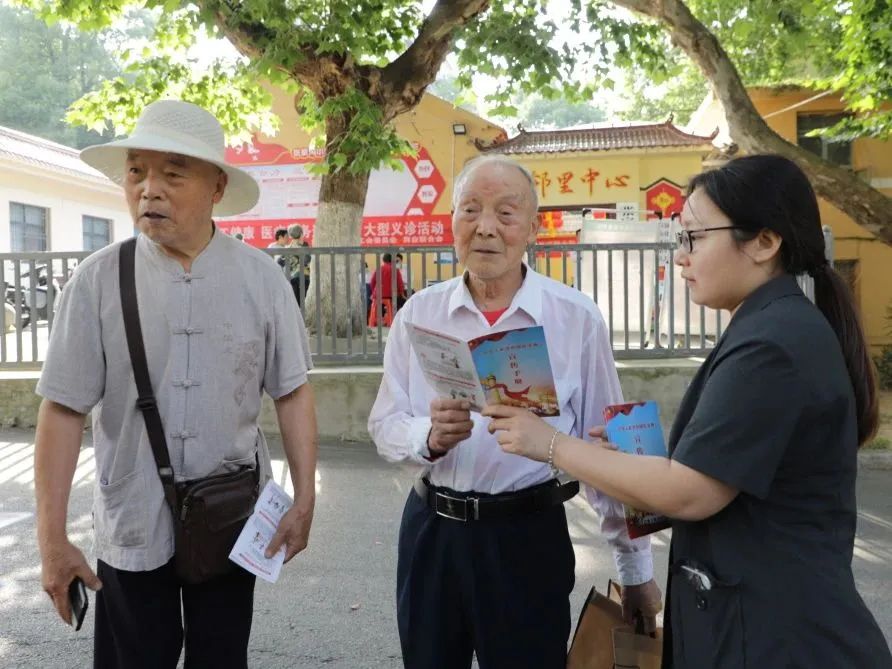 答案……"张家沟小区邻里中心,丹江口市法院干警杨朴丹手捧民法典宣传