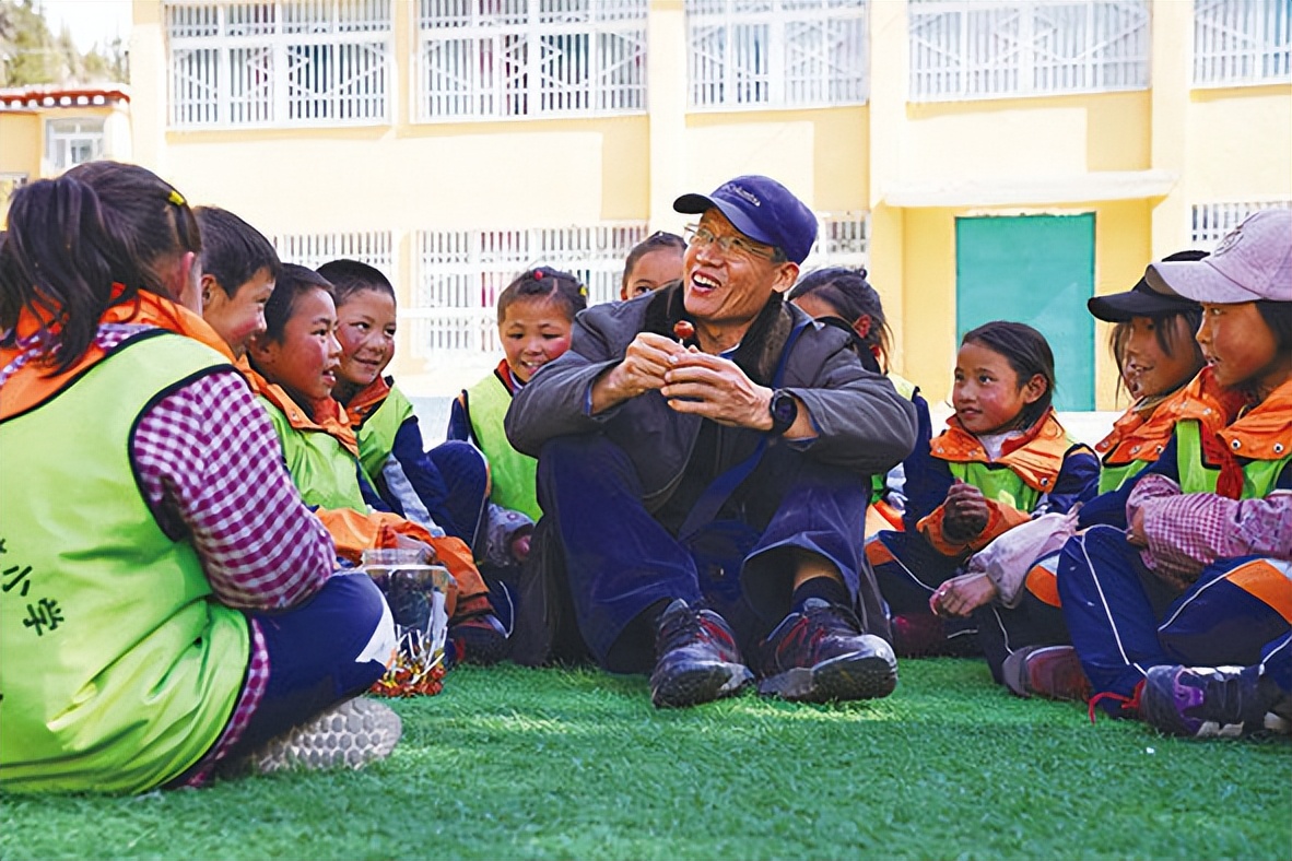 5月1日,在类乌齐县伊日乡小学,李纯民(中)和学生们交流.