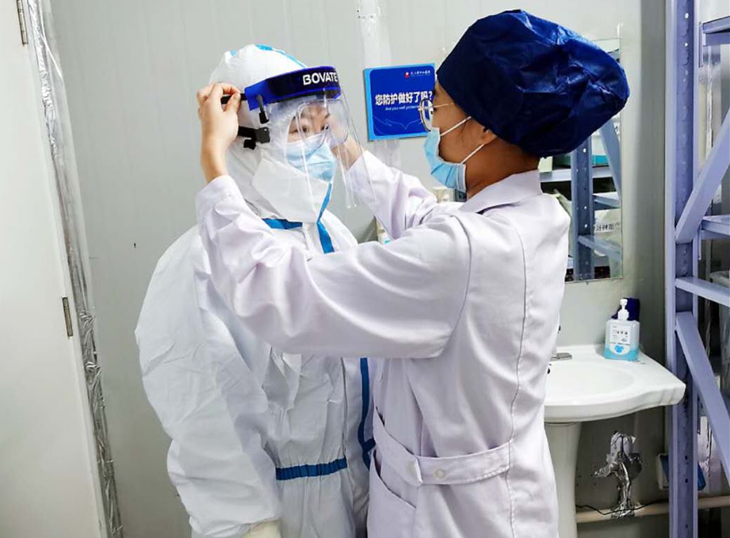 图说:医疗队员姜琳芸在为队友确认防护服的正确穿戴出征武汉"满月"了