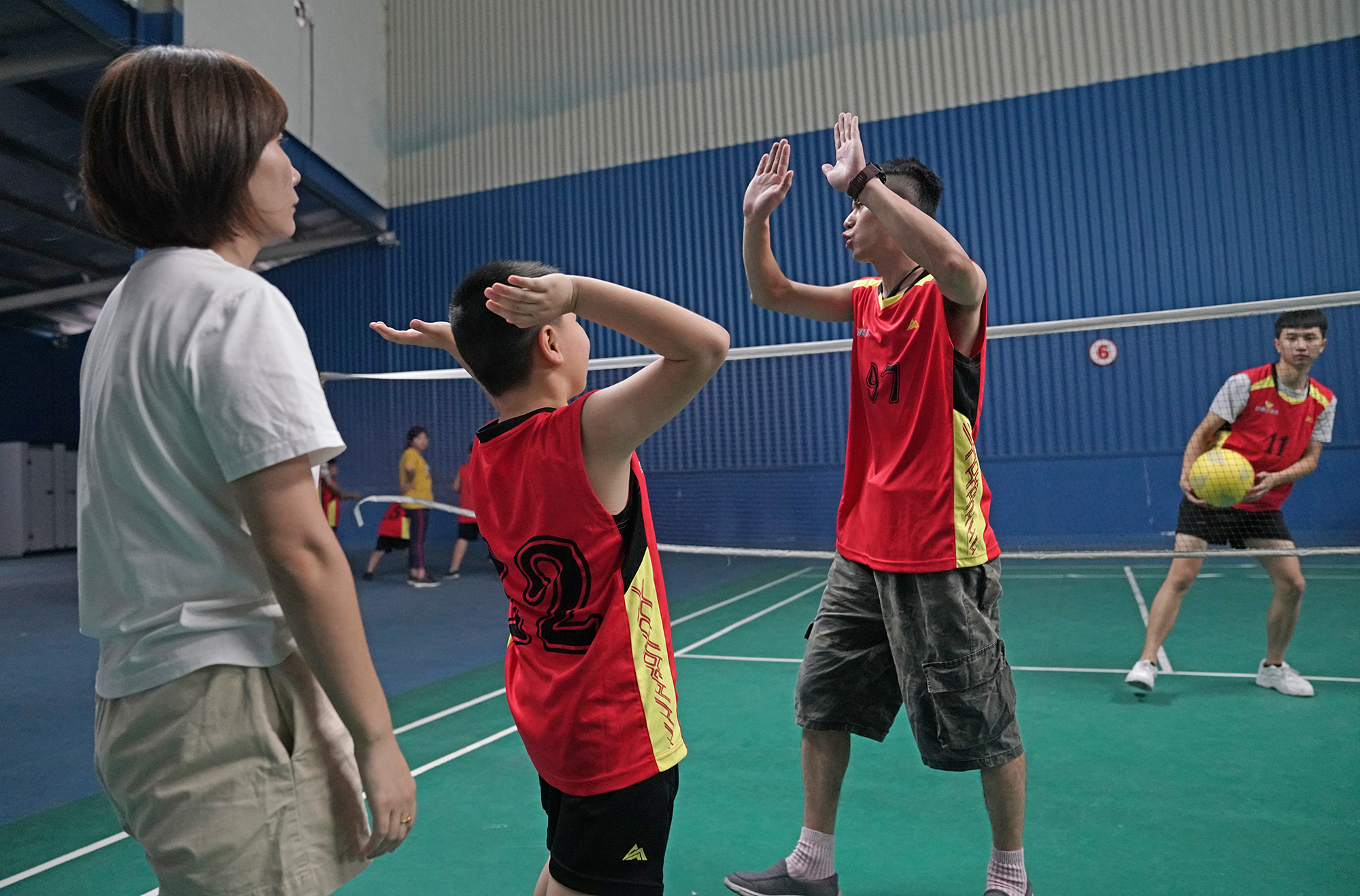 一个自闭症孩子在排球课上表现不错,他兴奋地和教练击掌祝贺.