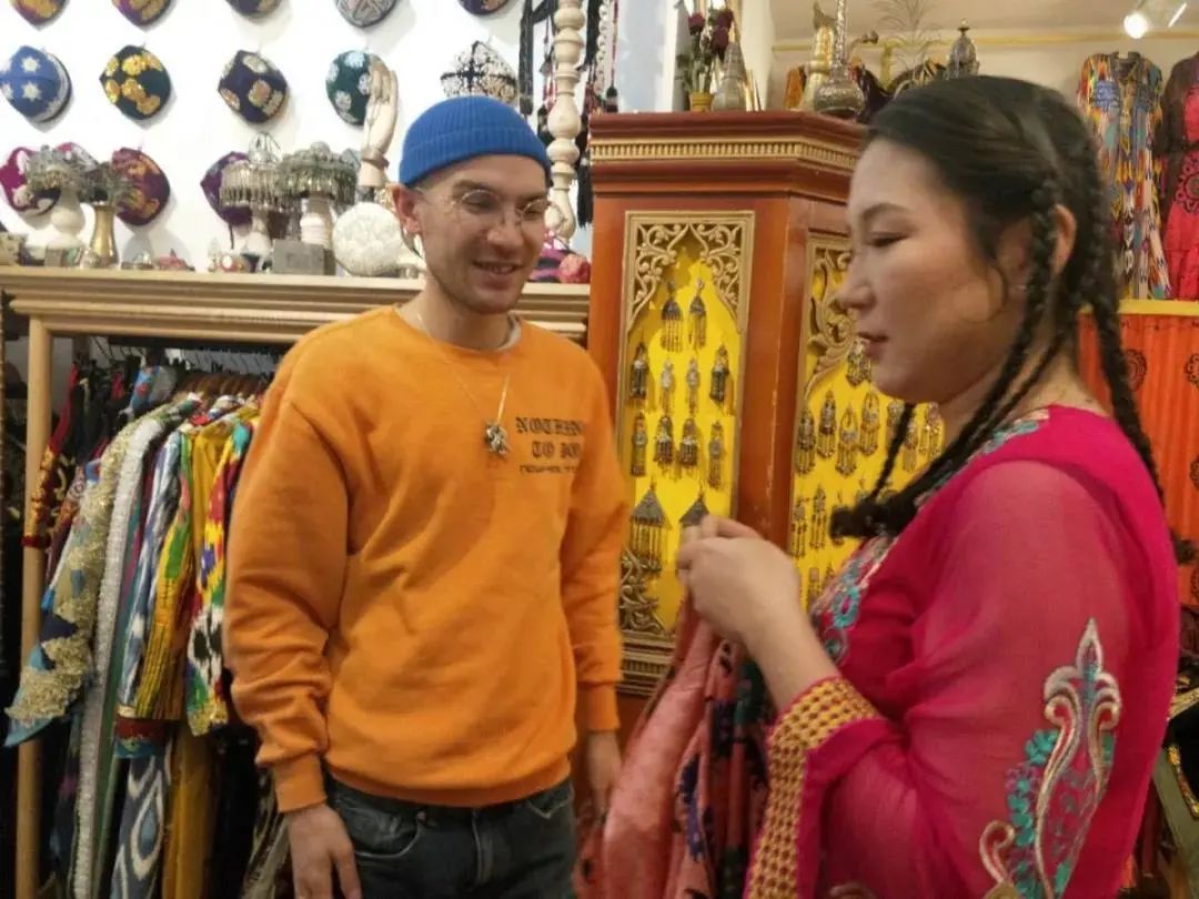 边眼镜,着装时髦的年轻人正在忙着接待顾客,小伙子名叫麦吾兰·图拉克