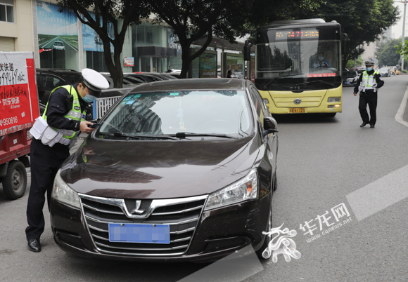 渝北区紫荆路,交巡警正在试图联系将车停在公交车港湾出口的车主挪车.